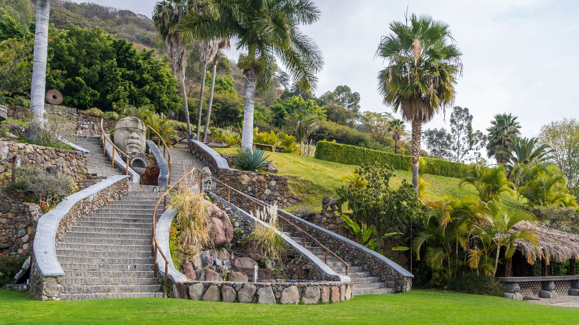 Jardin tropical paysager avec pelouse impeccable, palmiers et escaliers en pierre